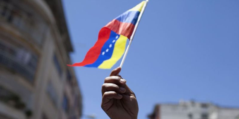 An opposition supporter waves a Venezuelan national flag as she attends a rally in Caracas