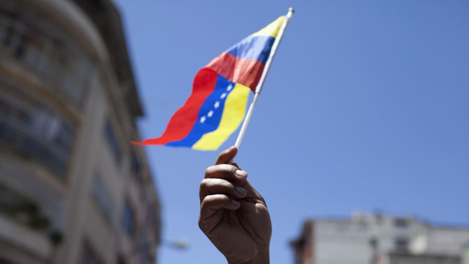 An opposition supporter waves a Venezuelan national flag as she attends a rally in Caracas