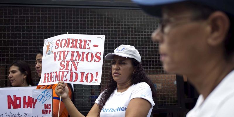 A protester holds a placard which reads "Surviving without remedy" during a gathering in demand for medicines in Caracas