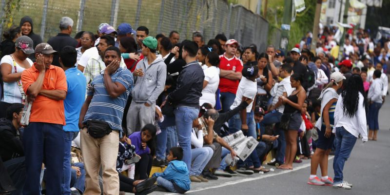 People line up outside a state-run Bicentenario supermarket in Caracas