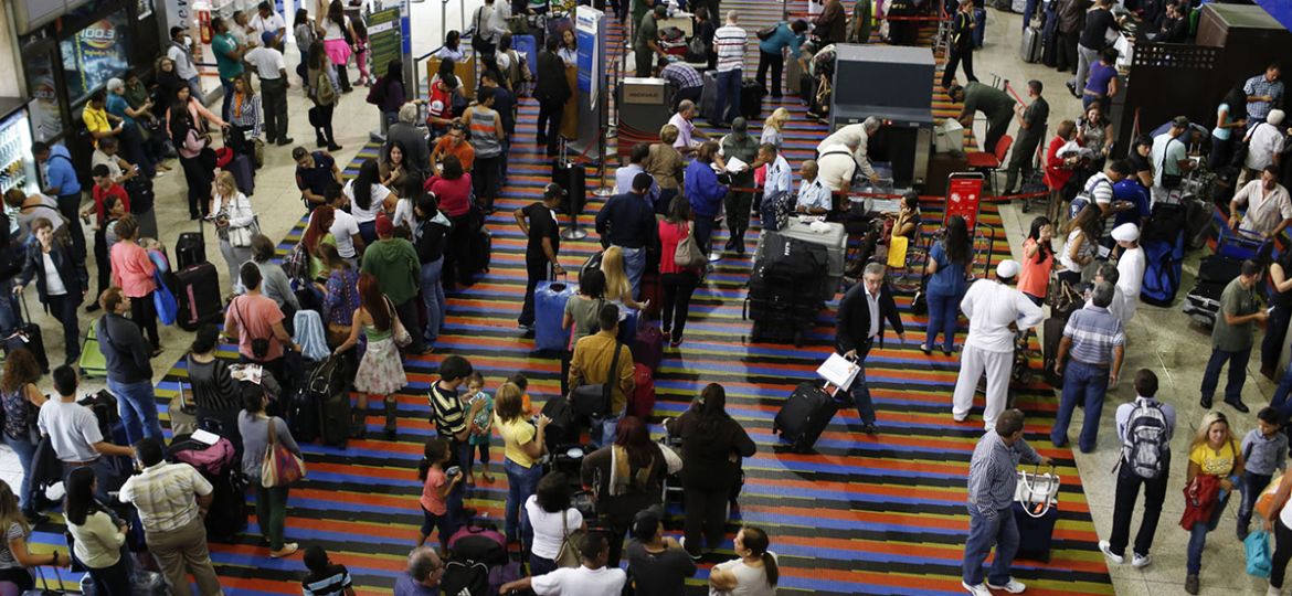 Passengers line up for the security checkpoint at Simon Bolivar airport in La Guaira