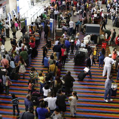 Passengers line up for the security checkpoint at Simon Bolivar airport in La Guaira