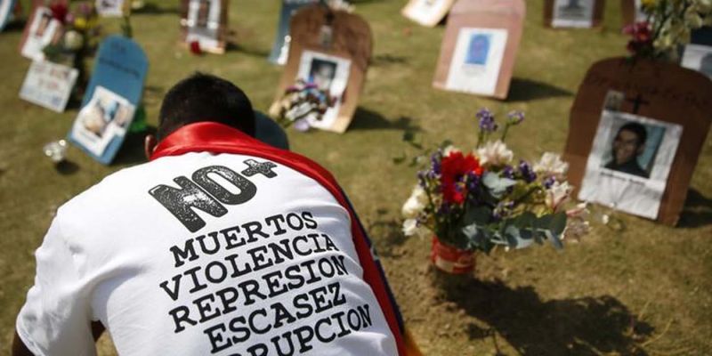 Una persona pone velas frente a unas simulaciones de tumbas con fotografías de víctimas de violencia, durante una protesta contra el gobierno de Nicolás Maduro, en Caracas