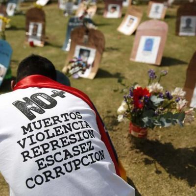 Una persona pone velas frente a unas simulaciones de tumbas con fotografías de víctimas de violencia, durante una protesta contra el gobierno de Nicolás Maduro, en Caracas