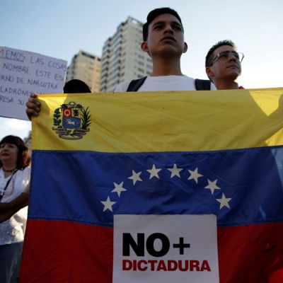 An opposition supporter holds a Venezuelan flag with a sign that reads "No more dictatorship" during a protest against Venezuelan President Nicolas Maduro's government, in Caracas