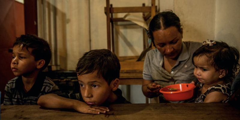 Oriana Caraballo, feeds her children Brayner, 8, Rayman, 6, and Sofia, 22 months, at a soup kitchen in Los Teques, Venezuela.