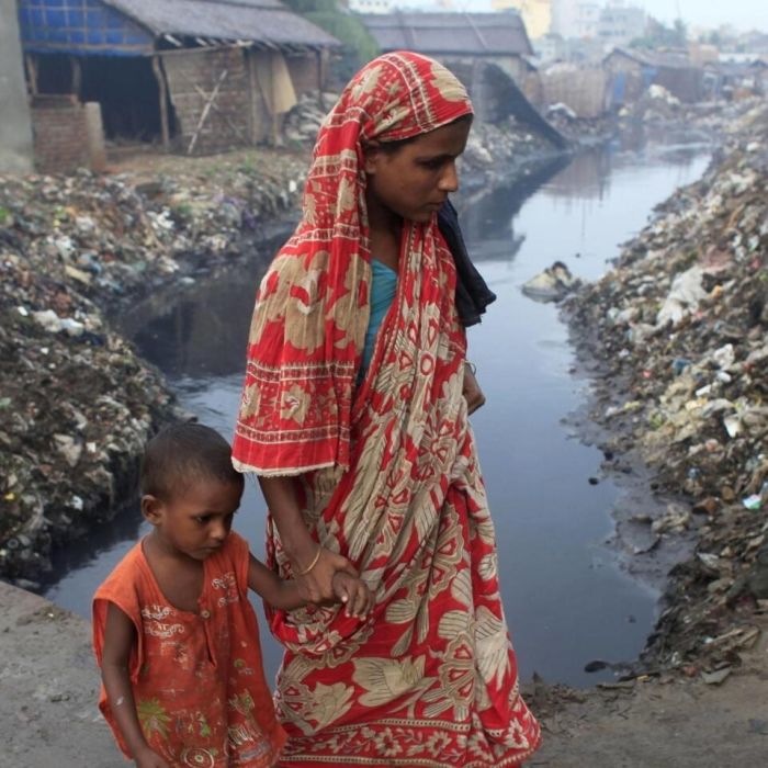 A woman and crosses a bridge with her child next to a tannery factory by the river Buriganga at Hazaribagh in Dhaka.